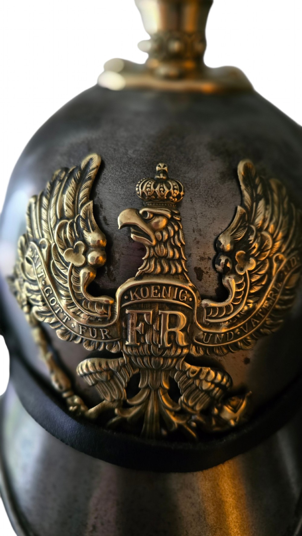 A WWI Prussian steel Pickelhaube helmet featuring a brass spiked top, a brass Prussian eagle emblem on the front, and a black strap. View VI