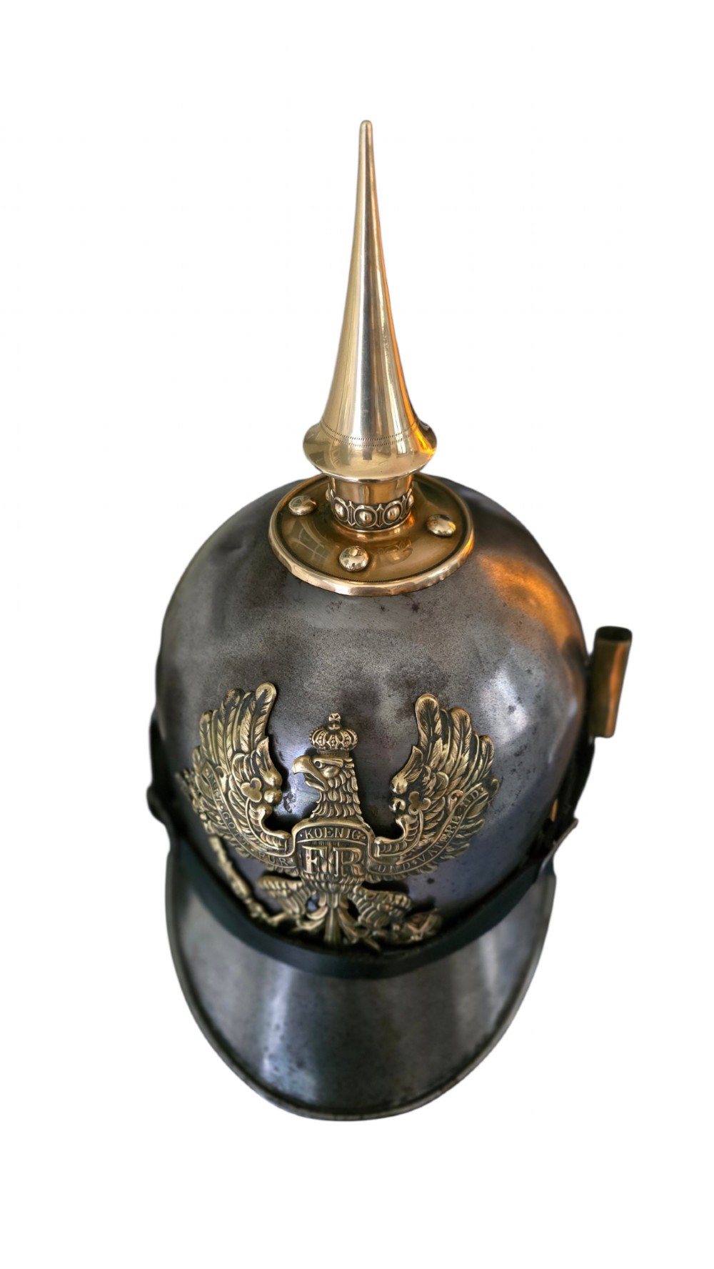A WWI Prussian steel Pickelhaube helmet featuring a brass spiked top, a brass Prussian eagle emblem on the front, and a black strap. View XI