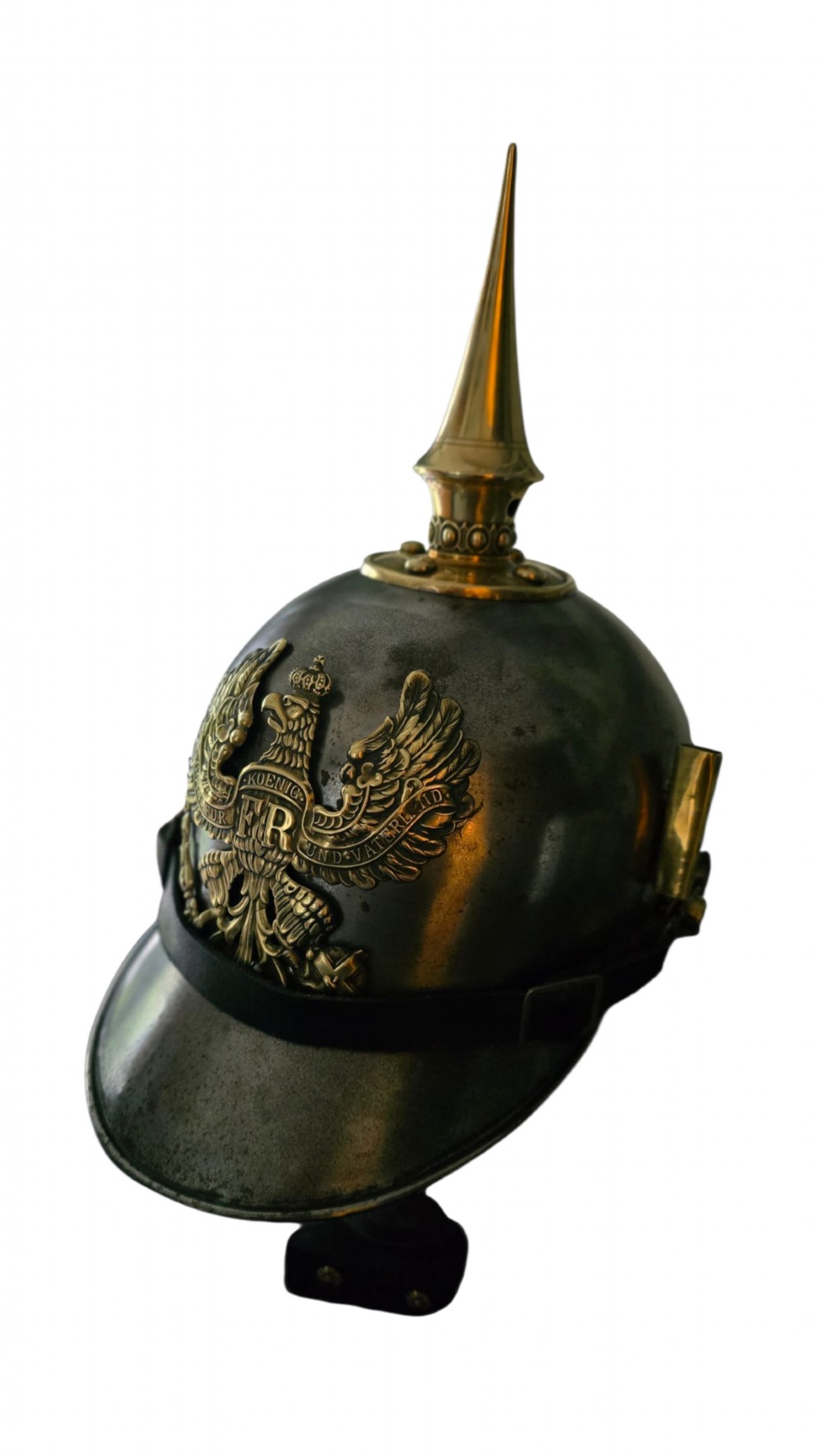 A WWI Prussian steel Pickelhaube helmet featuring a brass spiked top, a brass Prussian eagle emblem on the front, and a black strap. View XIV