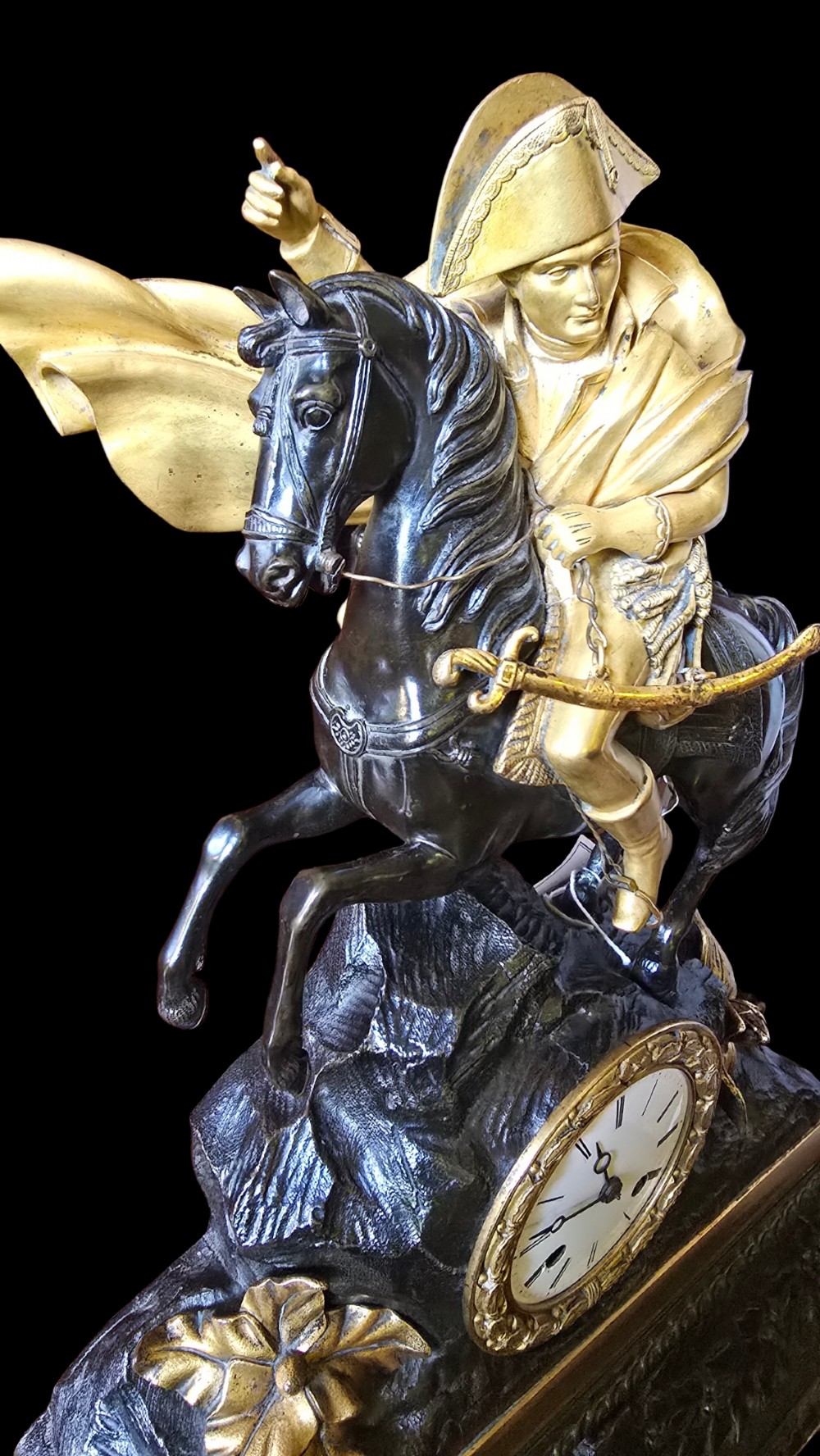 A 19th-century French mantel clock featuring a patinated and gilt bronze equestrian statue of Napoleon Bonaparte atop a base housing a white clock face with Roman numerals. View IV