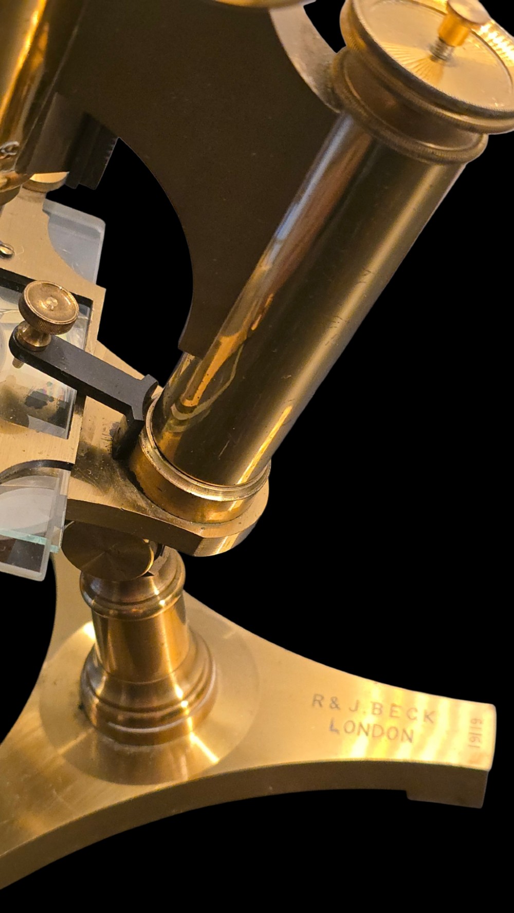 A Victorian lacquered brass binocular microscope featuring dual body tubes, knurled adjusting wheels, a stage plate, and a solid brass tripod foot. View VIII