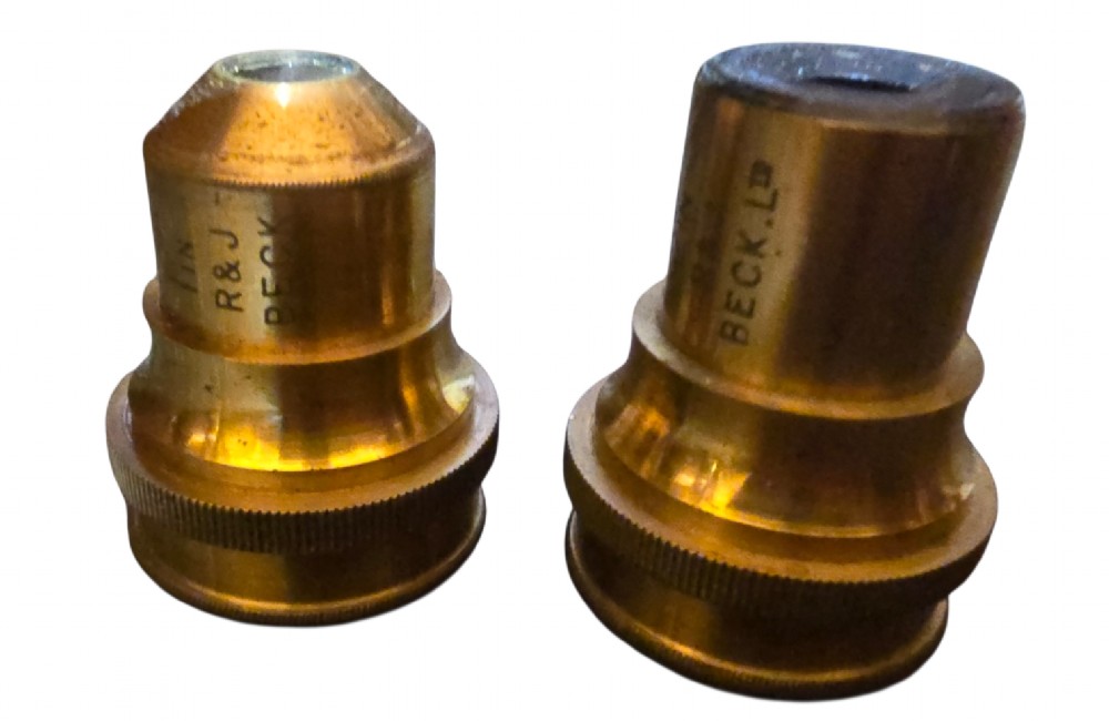 A Victorian lacquered brass binocular microscope featuring dual body tubes, knurled adjusting wheels, a stage plate, and a solid brass tripod foot. View XII