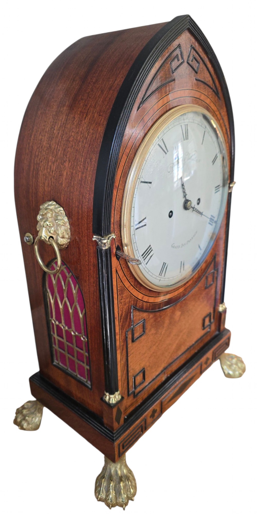 A Georgian mahogany lancet-top bracket clock featuring ebonised inlay, brass lion mask side handles, and decorative brass claw feet. View IX