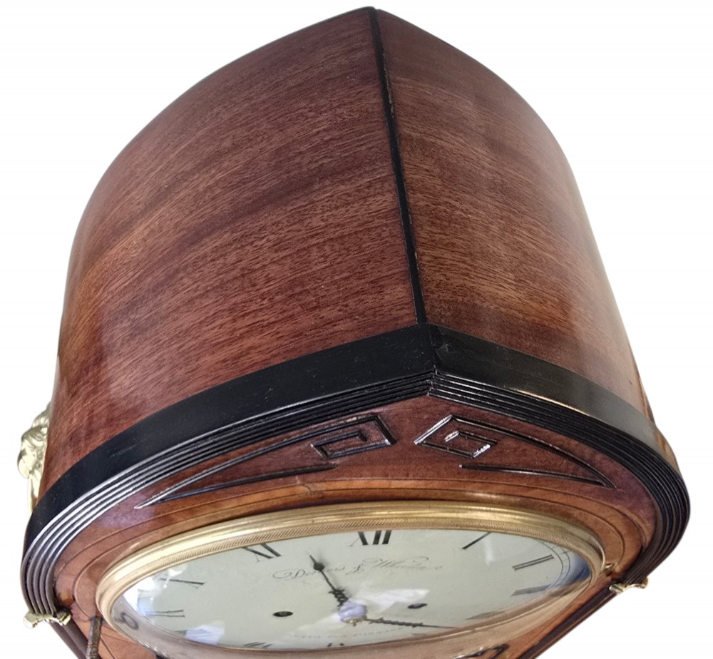 A Georgian mahogany lancet-top bracket clock featuring ebonised inlay, brass lion mask side handles, and decorative brass claw feet. View X