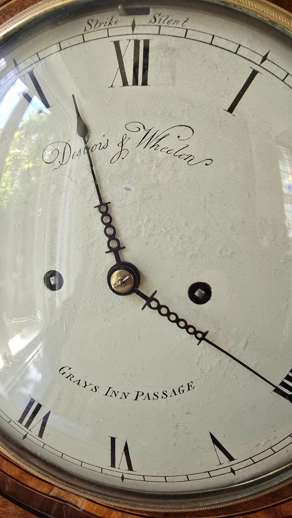 A Georgian mahogany lancet-top bracket clock featuring ebonised inlay, brass lion mask side handles, and decorative brass claw feet. View XI