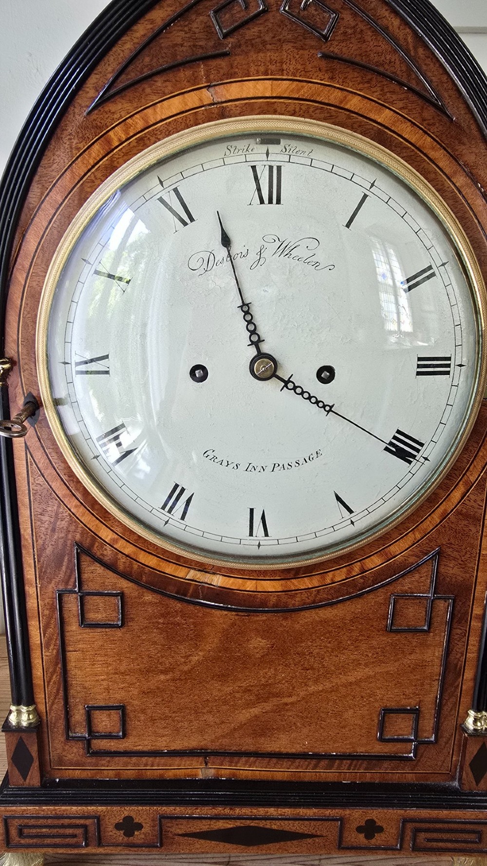 A Georgian mahogany lancet-top bracket clock featuring ebonised inlay, brass lion mask side handles, and decorative brass claw feet. View XII