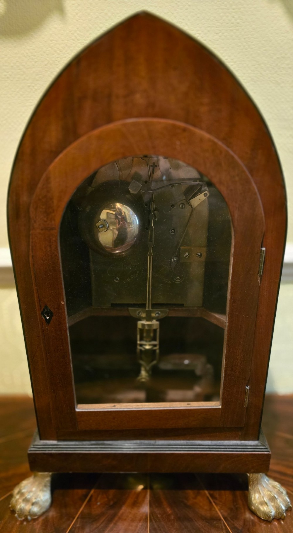 A Georgian mahogany lancet-top bracket clock featuring ebonised inlay, brass lion mask side handles, and decorative brass claw feet. View XIV