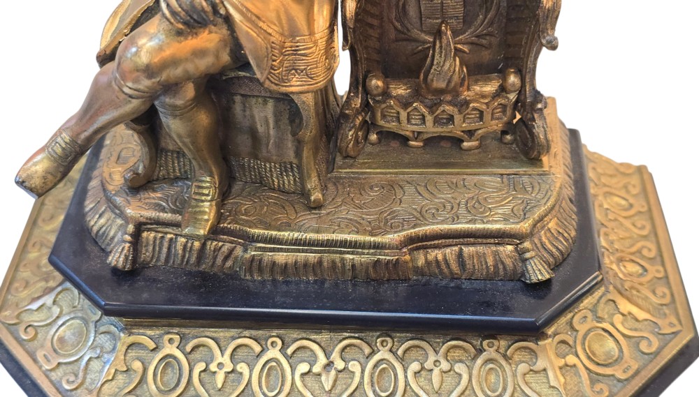 A 19th-century French gilt bronze sculpture depicting a seated gentleman in historic dress holding a quill, supported by an ornate black base with metallic scroll feet. View III