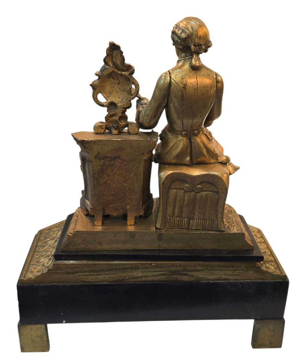 A 19th-century French gilt bronze sculpture depicting a seated gentleman in historic dress holding a quill, supported by an ornate black base with metallic scroll feet. View XI