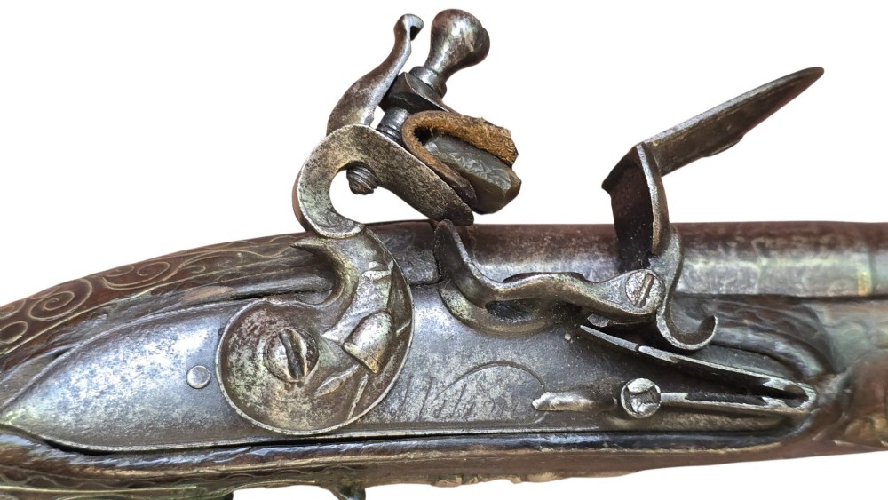 An early 19th-century Ottoman Balkan flintlock holster pistol featuring a dark wood stock inlaid with silver wire scrollwork and a cast brass pommel. View II