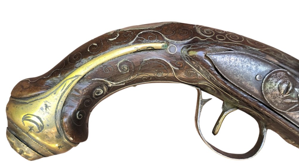An early 19th-century Ottoman Balkan flintlock holster pistol featuring a dark wood stock inlaid with silver wire scrollwork and a cast brass pommel. View III