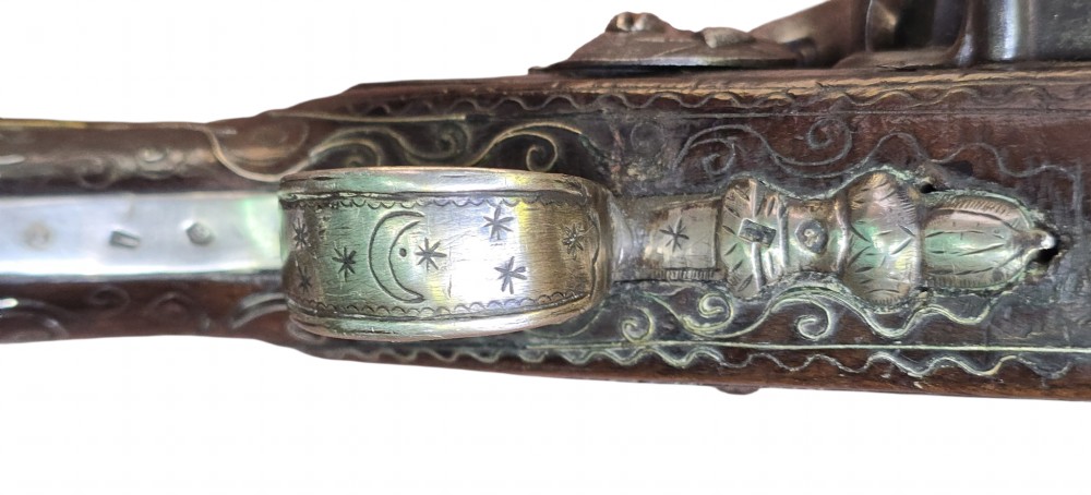 An early 19th-century Ottoman Balkan flintlock holster pistol featuring a dark wood stock inlaid with silver wire scrollwork and a cast brass pommel. View VII