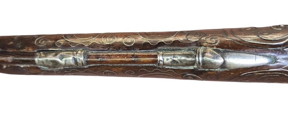 An early 19th-century Ottoman Balkan flintlock holster pistol featuring a dark wood stock inlaid with silver wire scrollwork and a cast brass pommel. View XI
