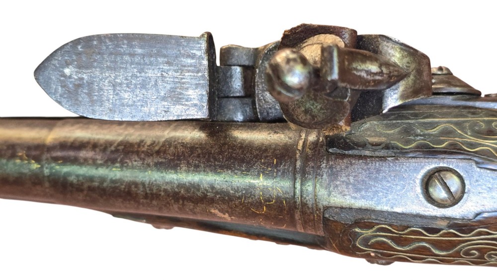 An early 19th-century Ottoman Balkan flintlock holster pistol featuring a dark wood stock inlaid with silver wire scrollwork and a cast brass pommel. View XII