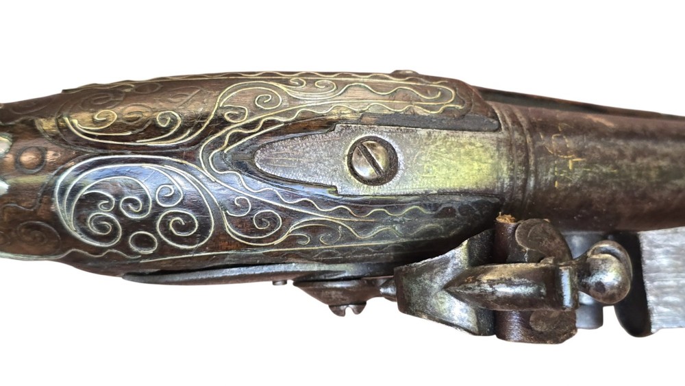 An early 19th-century Ottoman Balkan flintlock holster pistol featuring a dark wood stock inlaid with silver wire scrollwork and a cast brass pommel. View XIII