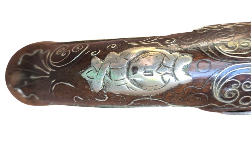 An early 19th-century Ottoman Balkan flintlock holster pistol featuring a dark wood stock inlaid with silver wire scrollwork and a cast brass pommel. View XIV