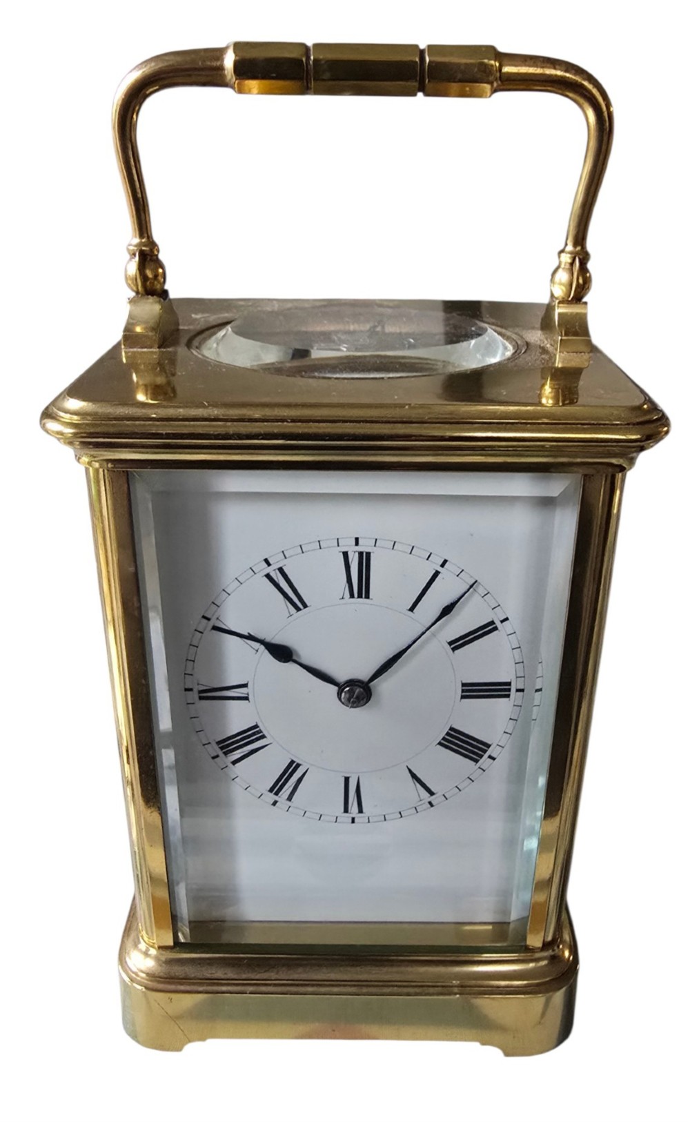 A rectangular French gilt-brass carriage clock featuring bevelled glass panels, a white enamel dial with Roman numerals, and a hinged top handle. View II