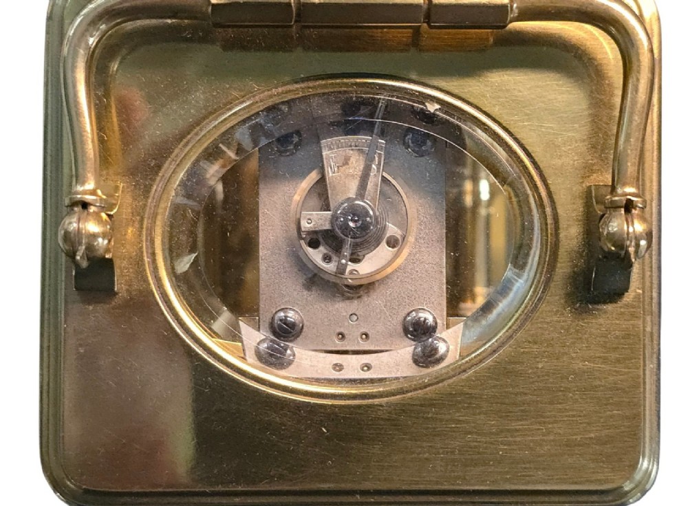A rectangular French gilt-brass carriage clock featuring bevelled glass panels, a white enamel dial with Roman numerals, and a hinged top handle. View X