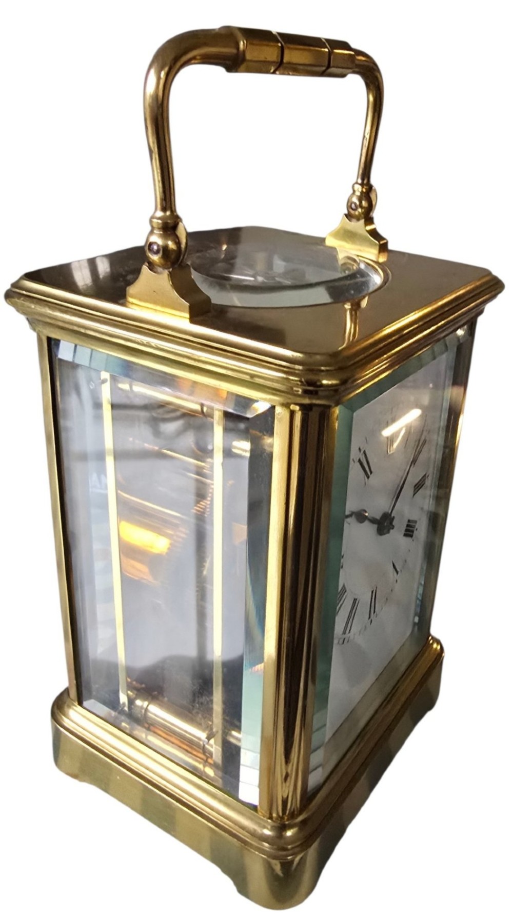 A rectangular French gilt-brass carriage clock featuring bevelled glass panels, a white enamel dial with Roman numerals, and a hinged top handle. View XIII