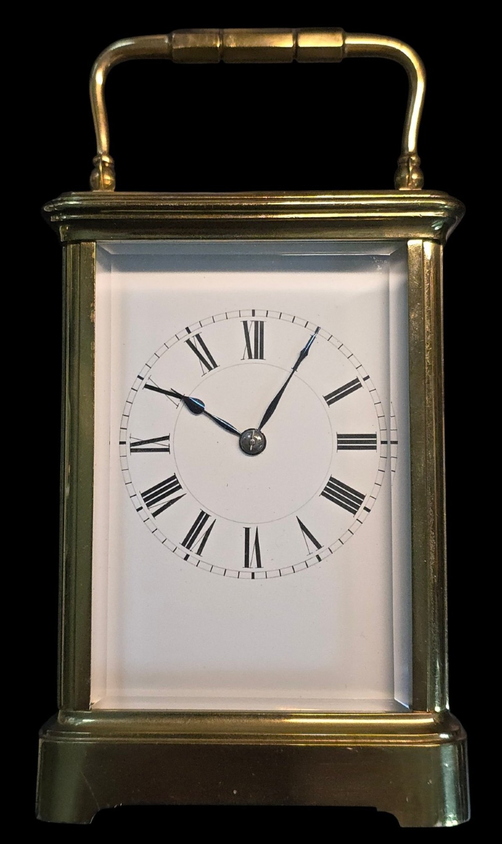 A rectangular French gilt-brass carriage clock featuring bevelled glass panels, a white enamel dial with Roman numerals, and a hinged top handle. View XIV