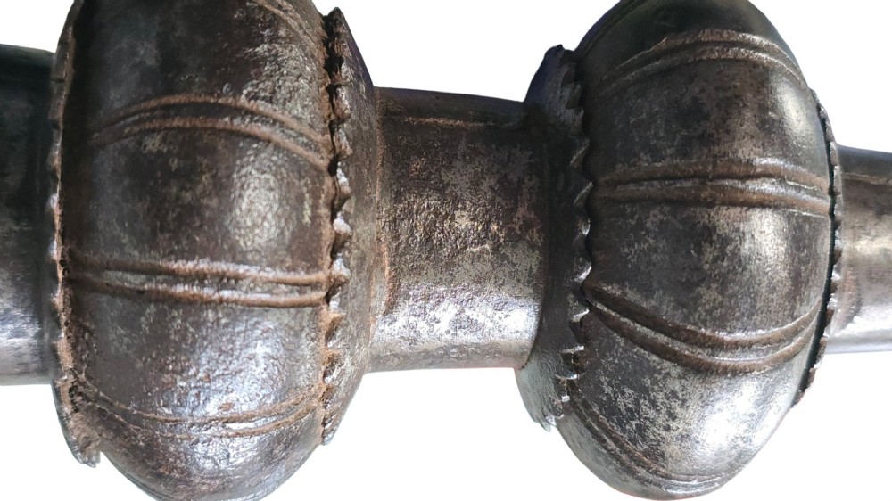 A 17th-century forged iron spear butt with a tapered spike and two ribbed knops, mounted vertically on a dark square stand. View V