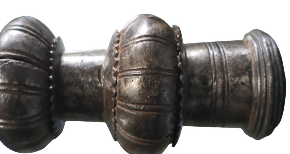 A 17th-century forged iron spear butt with a tapered spike and two ribbed knops, mounted vertically on a dark square stand. View VII