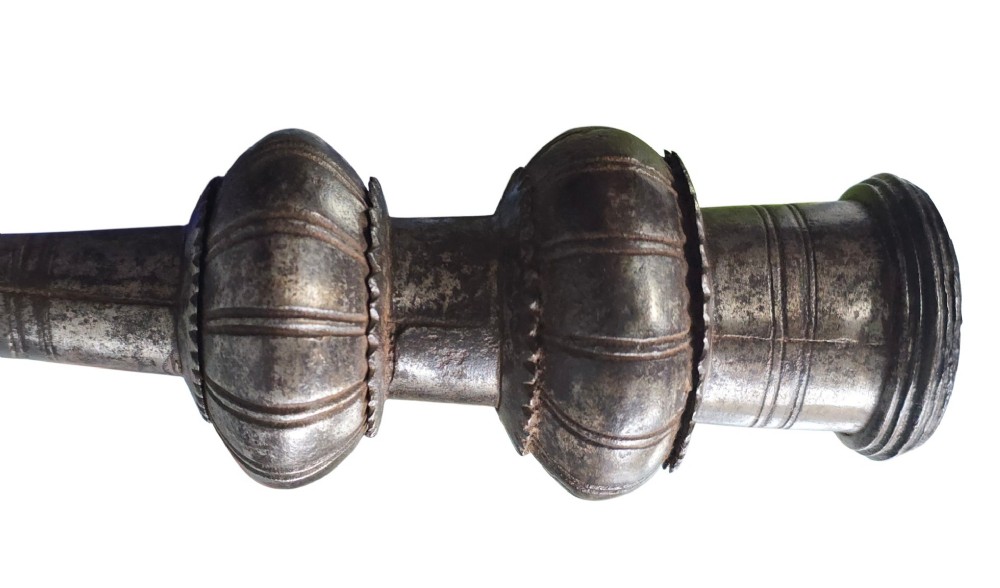 A 17th-century forged iron spear butt with a tapered spike and two ribbed knops, mounted vertically on a dark square stand. View IX