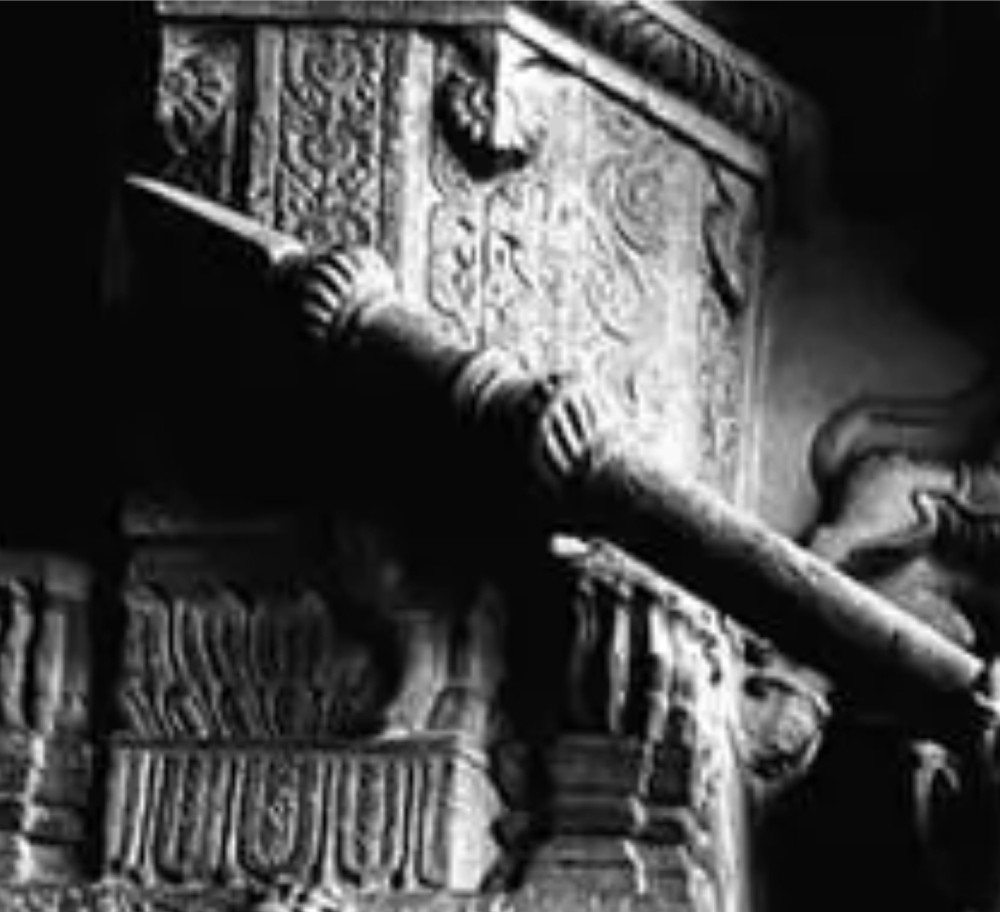 A 17th-century forged iron spear butt with a tapered spike and two ribbed knops, mounted vertically on a dark square stand. View XV