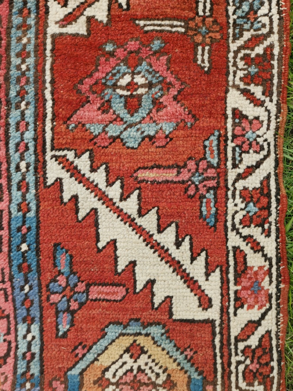 A rectangular Persian Heriz hand-knotted wool carpet featuring a red geometric field with a central star medallion, cream corner spandrels, and multi-banded borders. View VIII