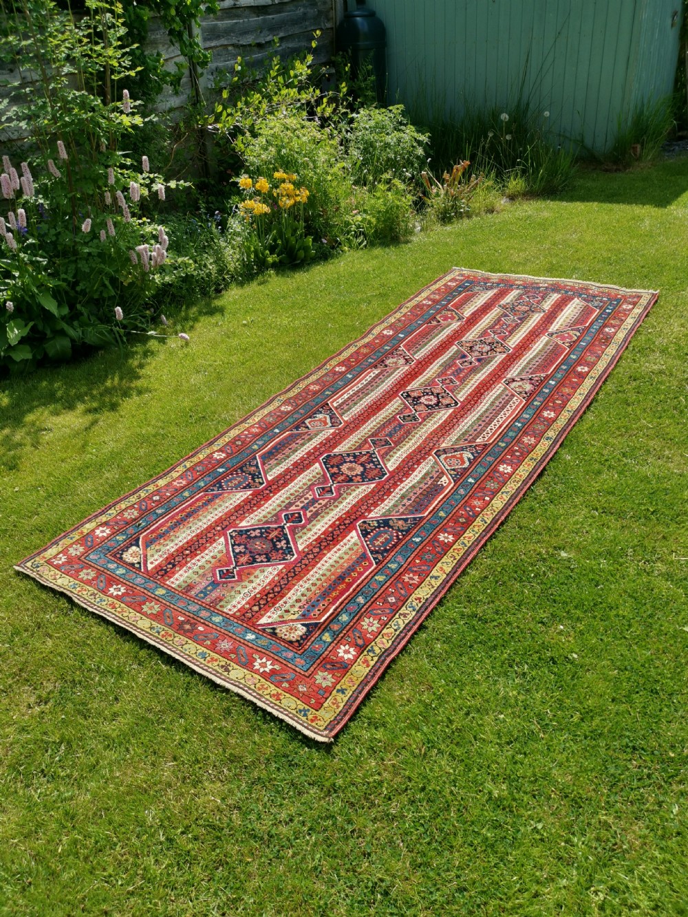 A long hand-knotted antique Caucasian Karabagh wool runner rug featuring central diamond medallions and geometric borders in red, blue, and yellow. View II