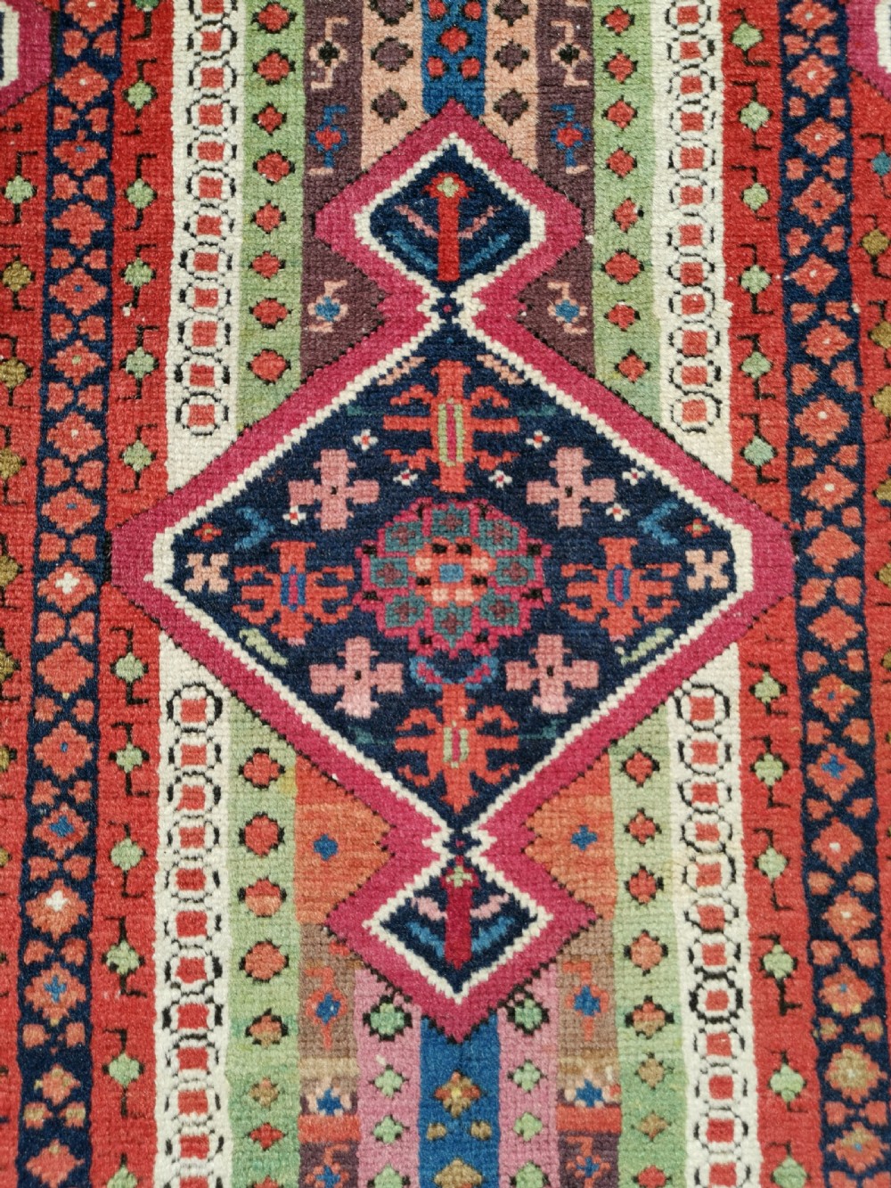 A long hand-knotted antique Caucasian Karabagh wool runner rug featuring central diamond medallions and geometric borders in red, blue, and yellow. View IV