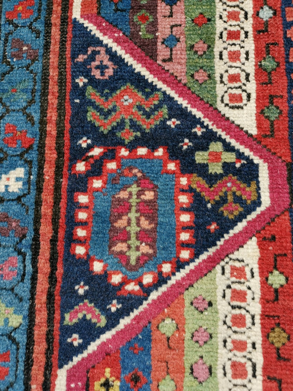 A long hand-knotted antique Caucasian Karabagh wool runner rug featuring central diamond medallions and geometric borders in red, blue, and yellow. View VII