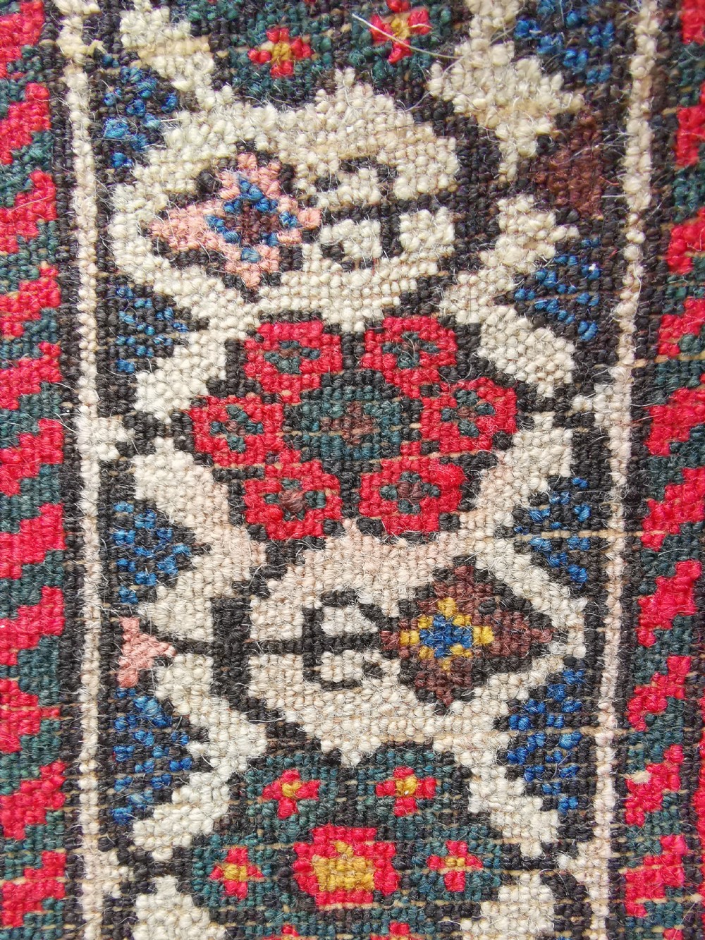 An antique Persian Malayer wool rug featuring a terracotta field, a central navy blue diamond medallion, and detailed geometric floral borders. View VII