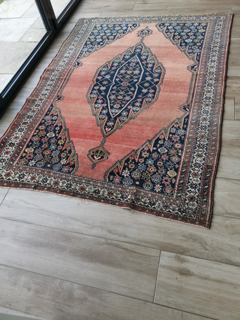 An antique Persian Malayer wool rug featuring a terracotta field, a central navy blue diamond medallion, and detailed geometric floral borders. View VIII
