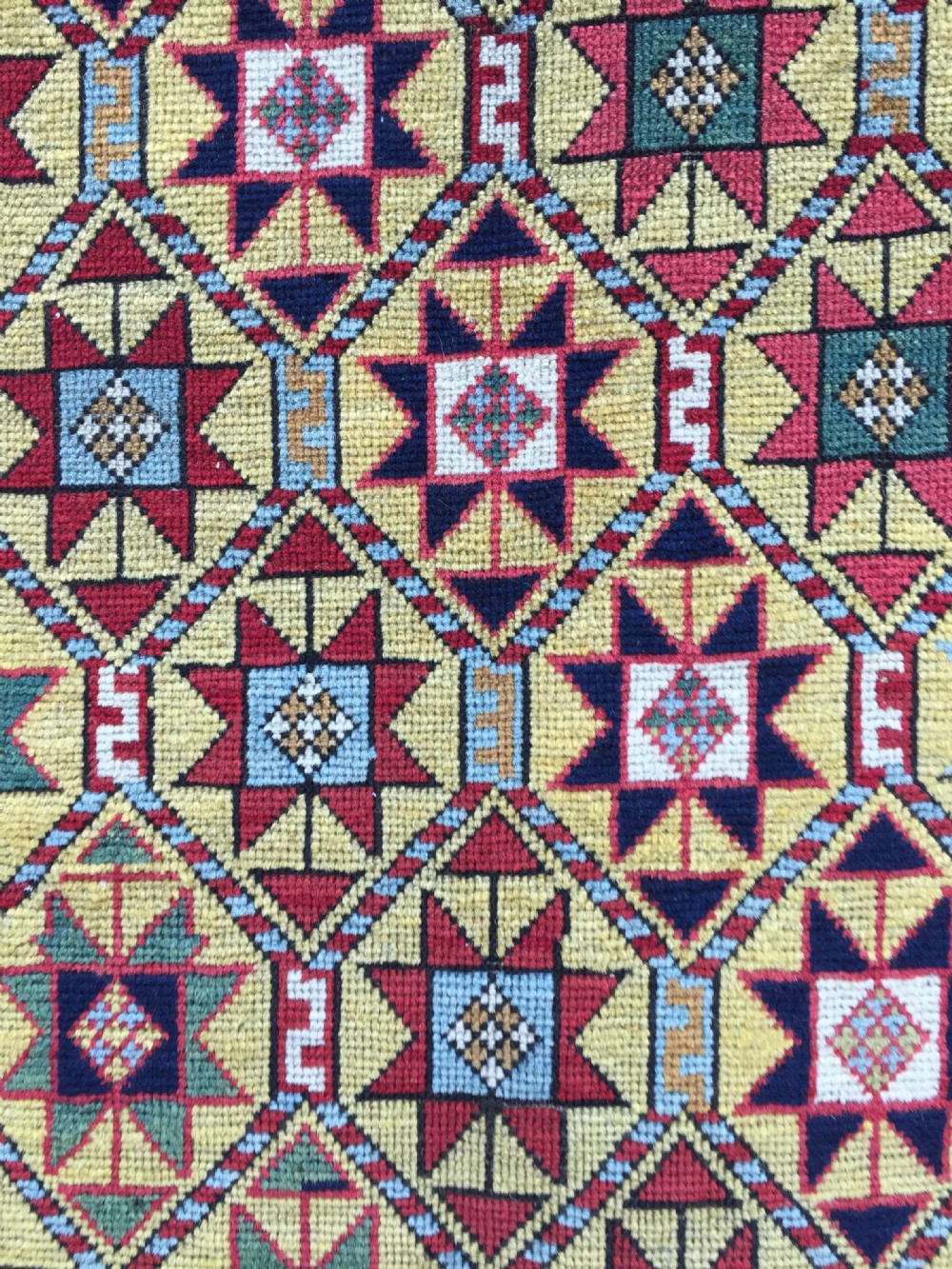 An antique hand-knotted Caucasian Gendje wool runner rug featuring a yellow central field with star motifs surrounded by a wide red border with rosettes. View III
