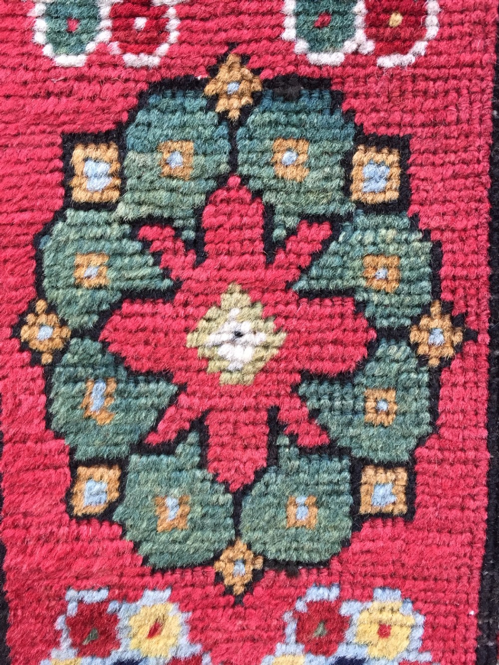 An antique hand-knotted Caucasian Gendje wool runner rug featuring a yellow central field with star motifs surrounded by a wide red border with rosettes. View V