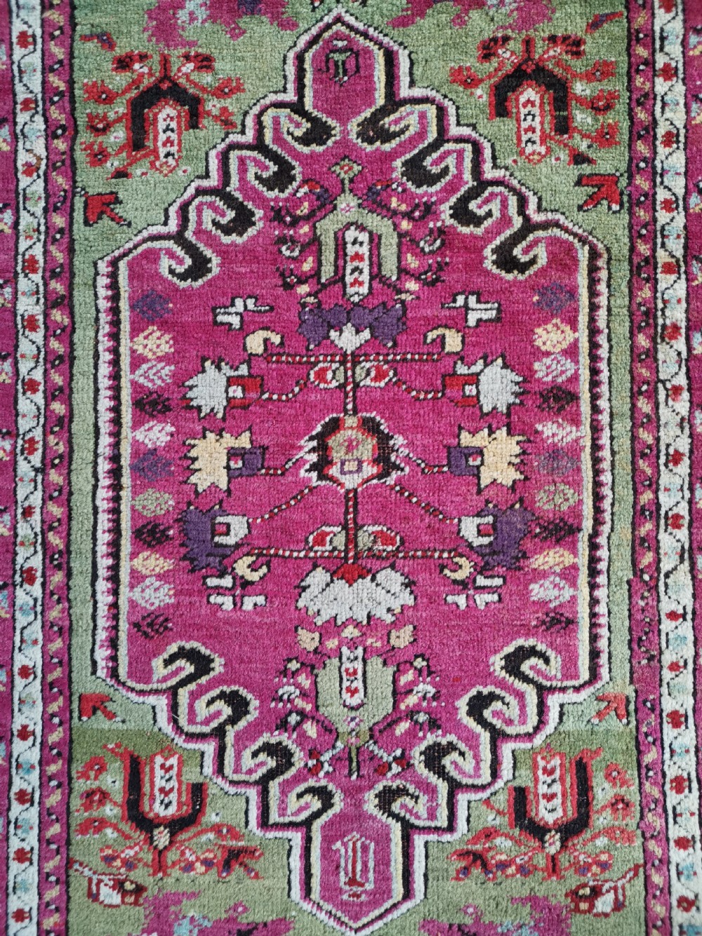 A hand-knotted Anatolian Kirsehir wool rug featuring a central magenta stepped medallion set within an olive green field and surrounded by multi-banded geometric borders. View II