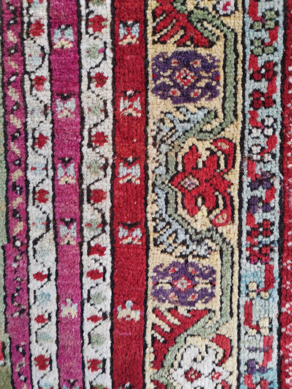 A hand-knotted Anatolian Kirsehir wool rug featuring a central magenta stepped medallion set within an olive green field and surrounded by multi-banded geometric borders. View IV