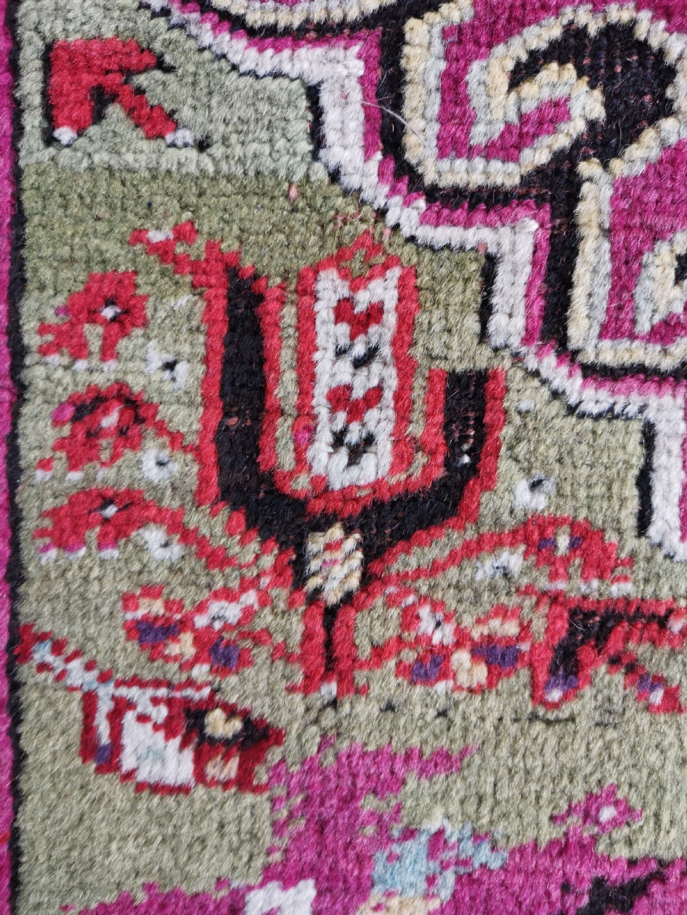 A hand-knotted Anatolian Kirsehir wool rug featuring a central magenta stepped medallion set within an olive green field and surrounded by multi-banded geometric borders. View VI