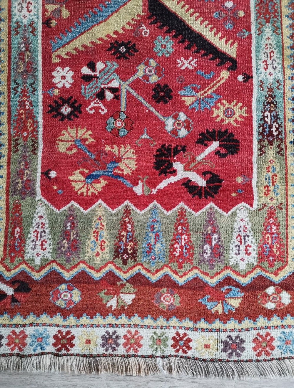 An antique hand-knotted Melas wool rug featuring a terracotta red central field with a stepped prayer arch motif and geometric multi-patterned borders. View IV