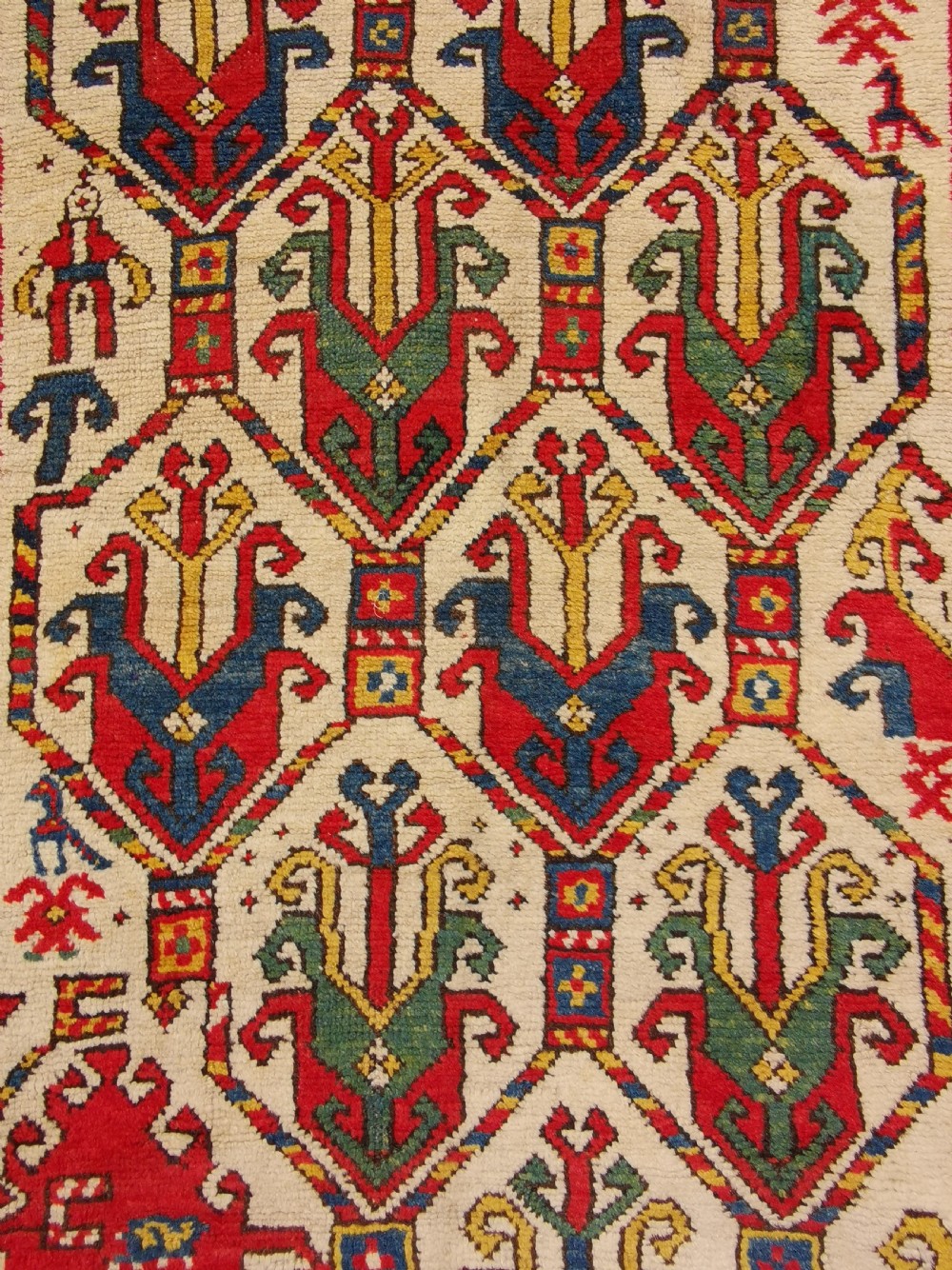 An antique hand-knotted Caucasian Gendje wool rug featuring an ivory central field with geometric lattice patterns framed by a wide red border. View VII