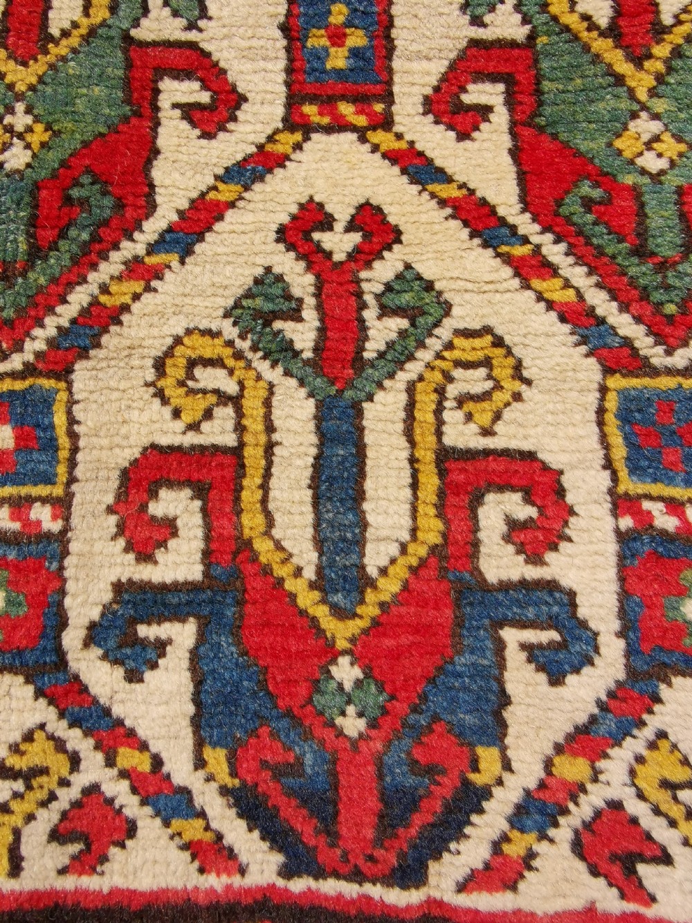 An antique hand-knotted Caucasian Gendje wool rug featuring an ivory central field with geometric lattice patterns framed by a wide red border. View VIII