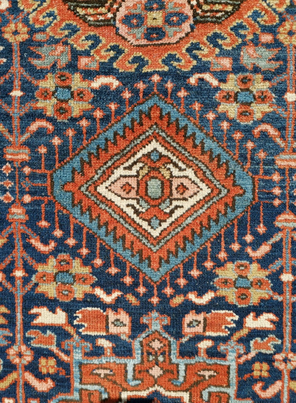 Hand-knotted antique Persian Karaja rug featuring a navy blue field with geometric diamond medallions, framed by multi-coloured decorative borders. View III