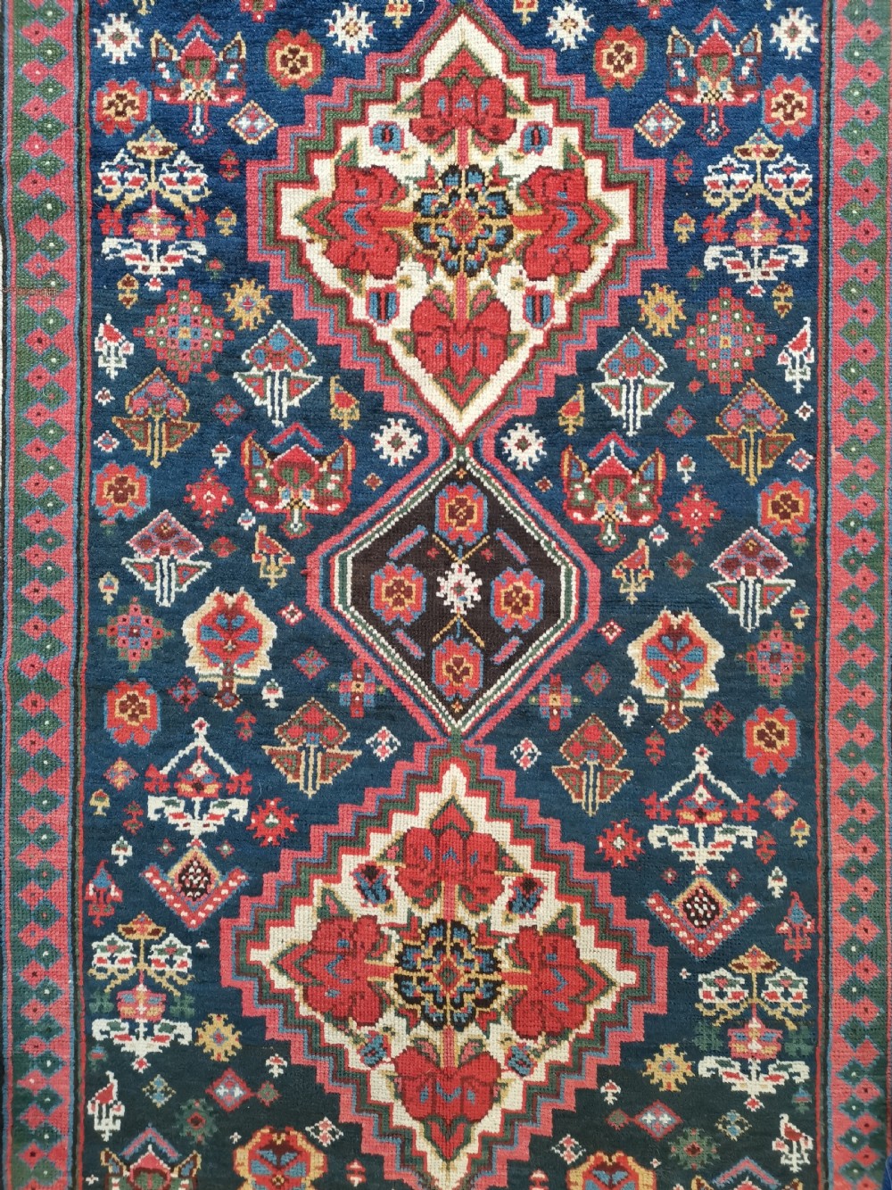 A hand-knotted Persian Veramin wool runner rug featuring diamond-shaped central medallions in crimson red, navy blue, and ivory set within a geometric border. View III
