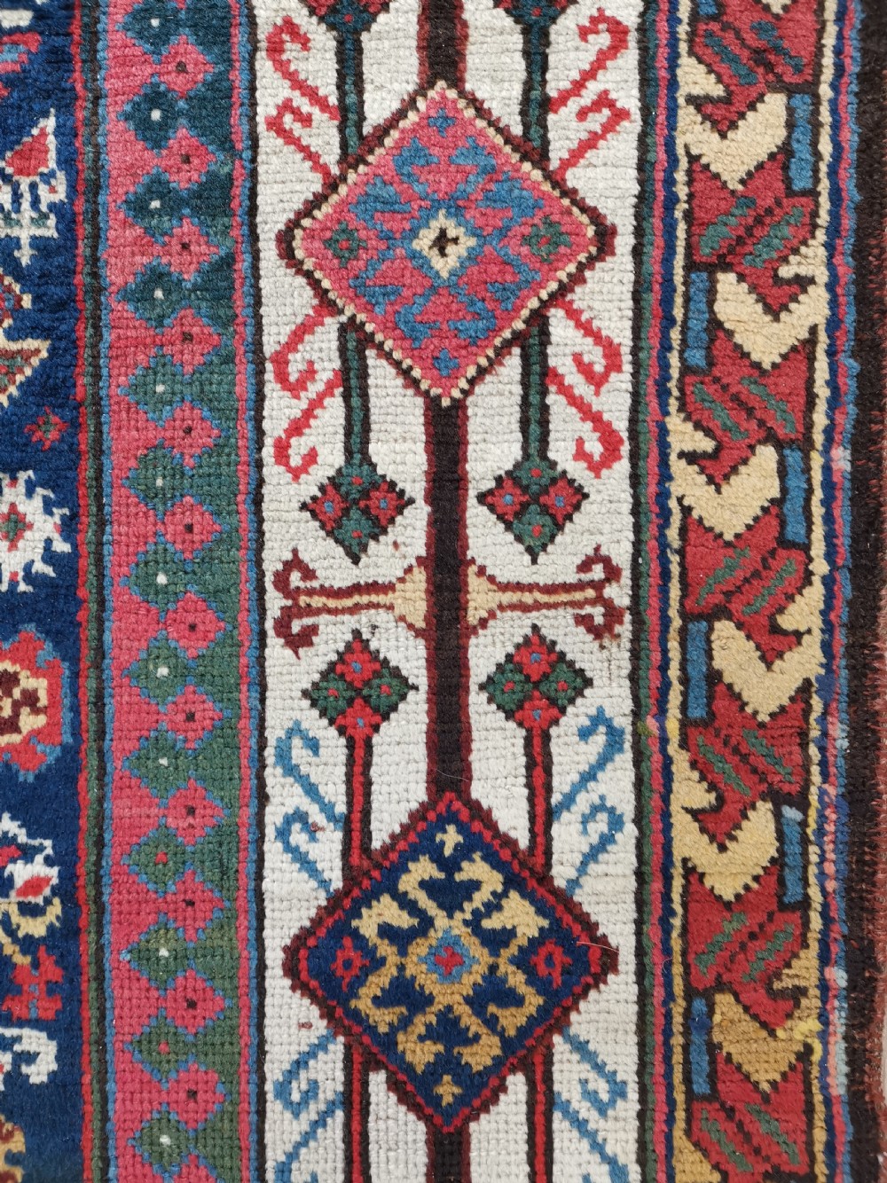 A hand-knotted Persian Veramin wool runner rug featuring diamond-shaped central medallions in crimson red, navy blue, and ivory set within a geometric border. View IV