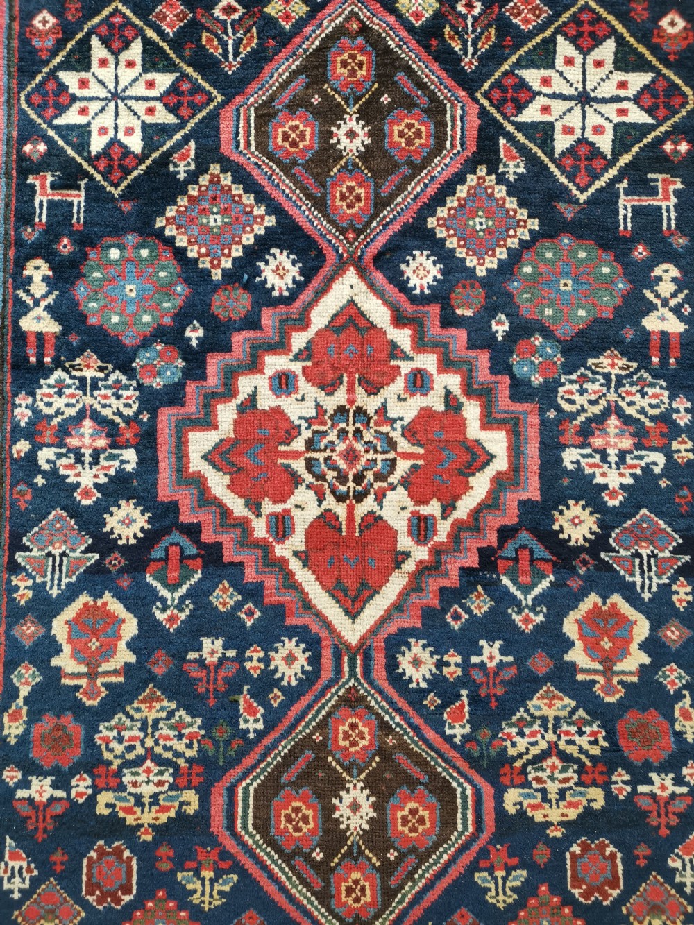 A hand-knotted Persian Veramin wool runner rug featuring diamond-shaped central medallions in crimson red, navy blue, and ivory set within a geometric border. View VI