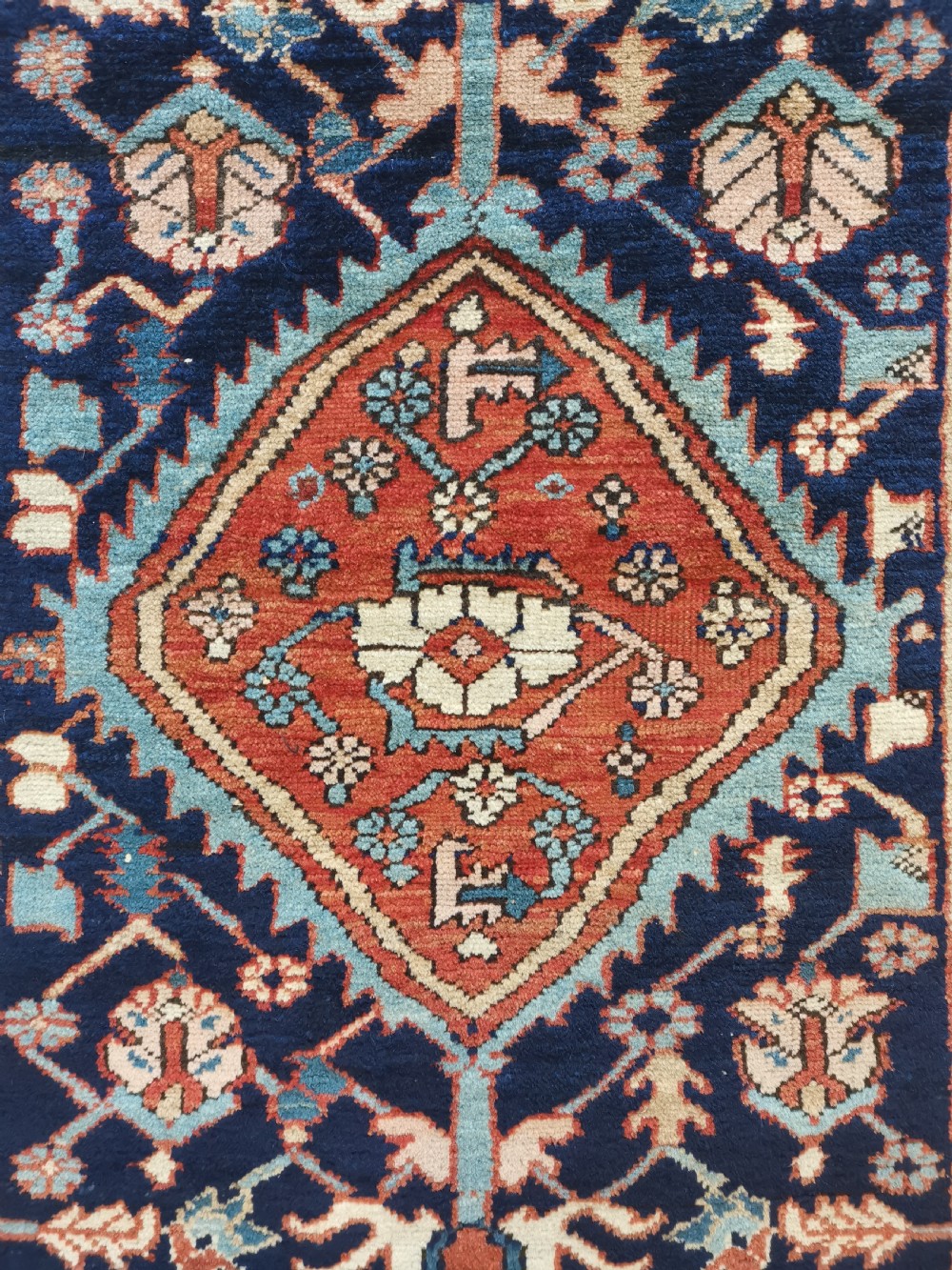 A hand-knotted antique Karaja wool rug featuring a navy field decorated with a central red geometric diamond medallion and colourful tribal motifs within a geometric border. View III