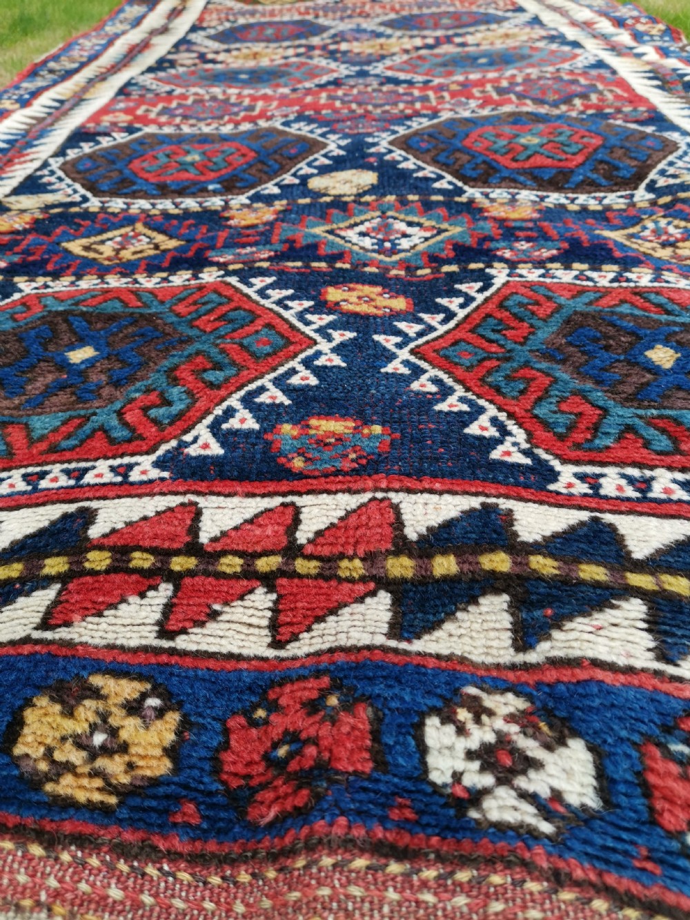 A hand-knotted tribal Jaf Kurdish wool rug featuring geometric hexagonal hooked motifs in deep navy blue, red, ochre, and cream. View II