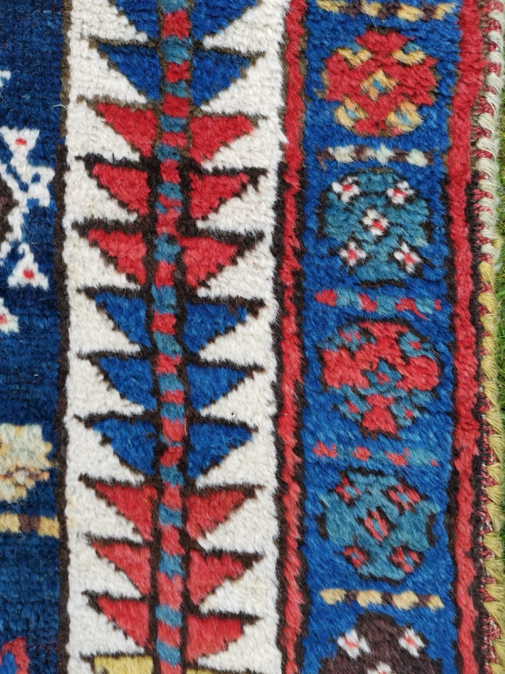 A hand-knotted tribal Jaf Kurdish wool rug featuring geometric hexagonal hooked motifs in deep navy blue, red, ochre, and cream. View III