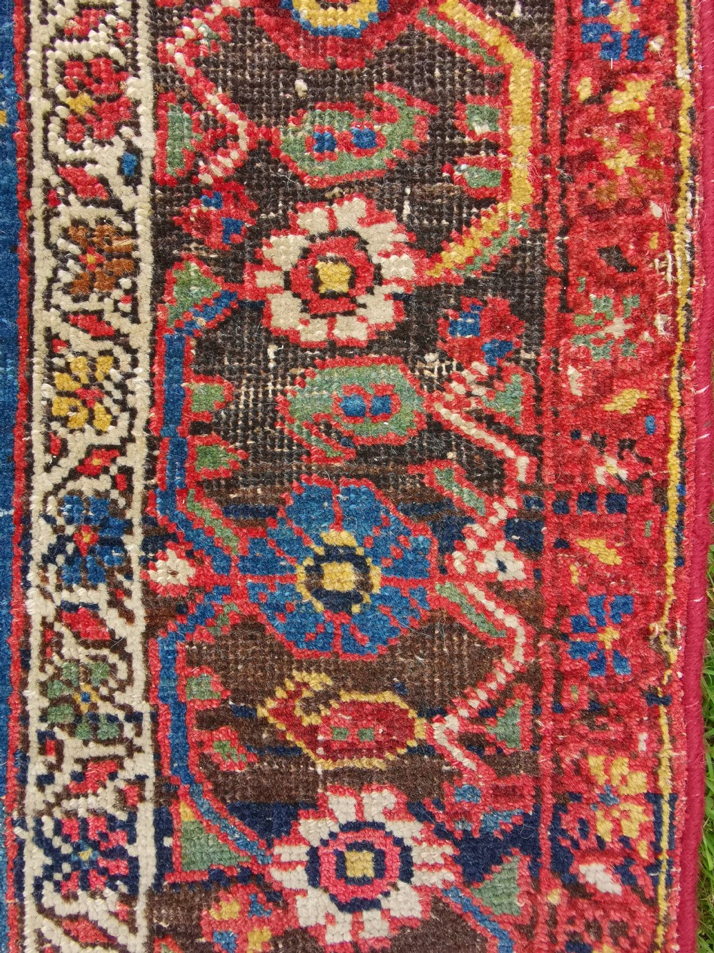 An antique hand-knotted Persian Bijar wool rug featuring a red central field, dark navy medallion, and geometric floral borders. View III